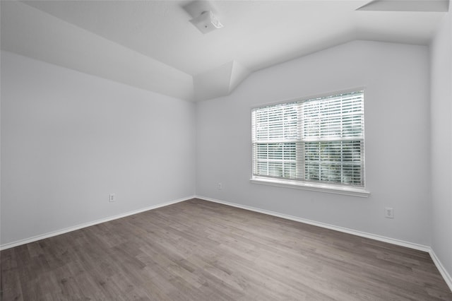 spare room featuring vaulted ceiling and hardwood / wood-style flooring