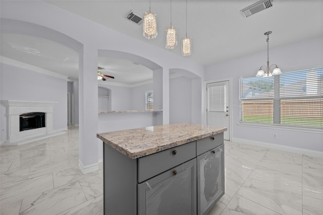 kitchen featuring ornamental molding, gray cabinetry, ceiling fan with notable chandelier, pendant lighting, and a kitchen island