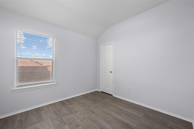 empty room with dark hardwood / wood-style floors and vaulted ceiling