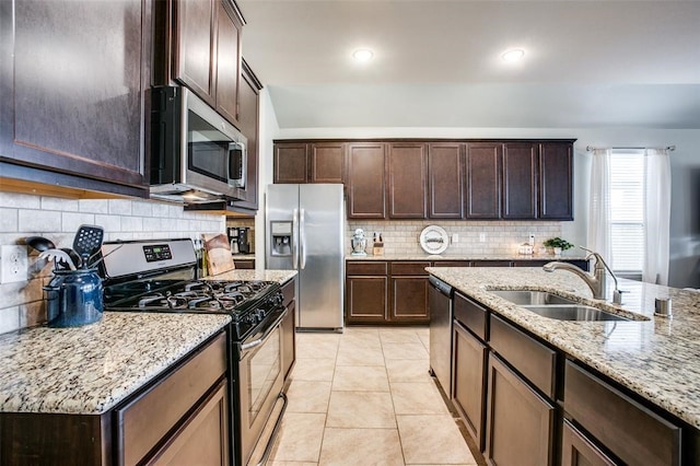 kitchen featuring light stone countertops, sink, stainless steel appliances, tasteful backsplash, and light tile patterned floors