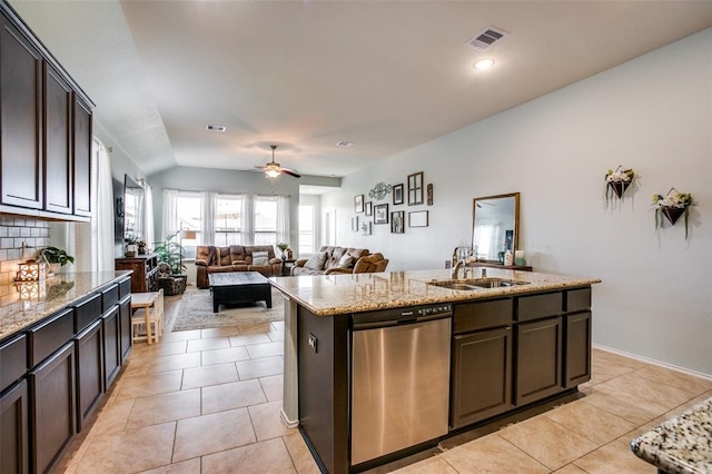 kitchen featuring dishwasher, a center island with sink, sink, light stone counters, and dark brown cabinetry