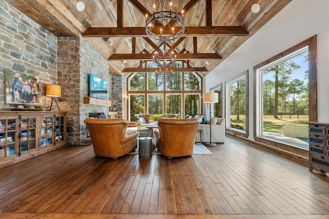 sunroom featuring vaulted ceiling with beams, wood ceiling, a fireplace, and a chandelier