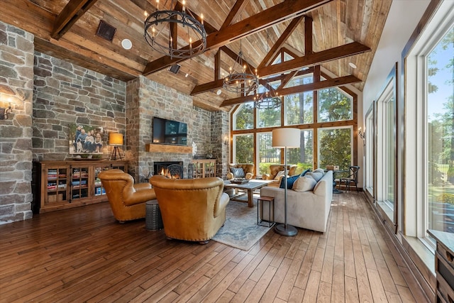 living room with a wealth of natural light, beam ceiling, wood-type flooring, high vaulted ceiling, and a chandelier