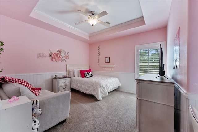 carpeted bedroom with a raised ceiling, ceiling fan, and ornamental molding