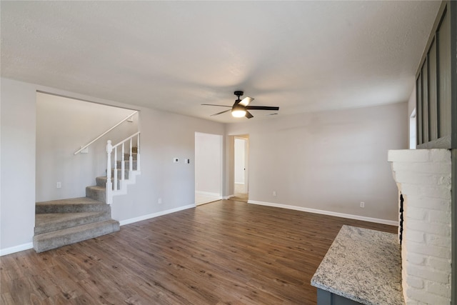 unfurnished living room with a textured ceiling, ceiling fan, and dark wood-type flooring