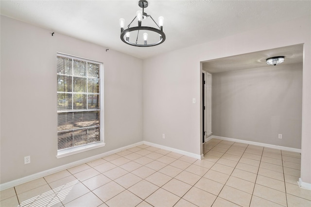 tiled spare room featuring a chandelier