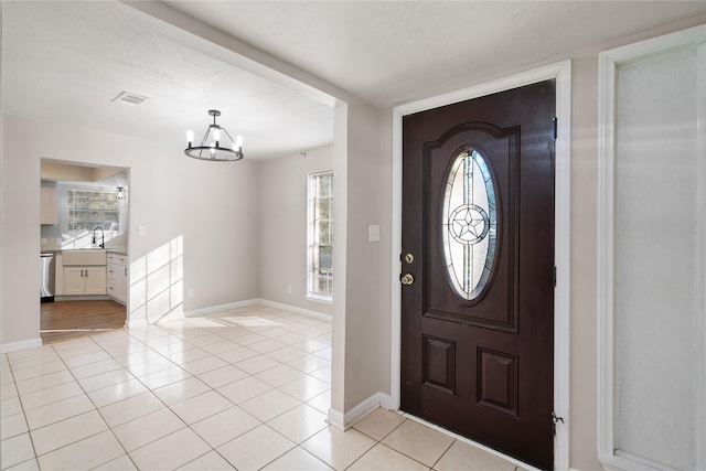 tiled foyer entrance featuring a textured ceiling, plenty of natural light, and a notable chandelier