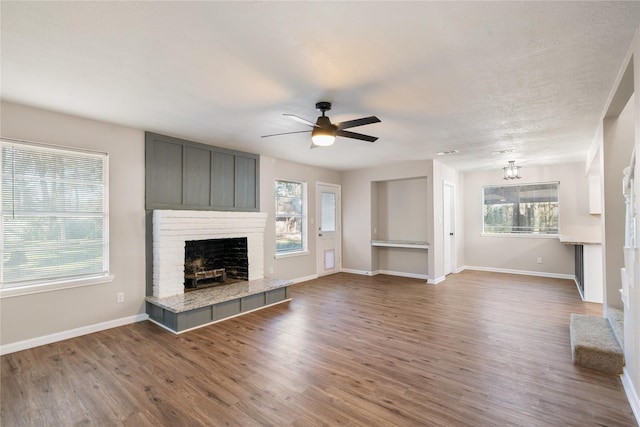 unfurnished living room with wood-type flooring, ceiling fan with notable chandelier, and a healthy amount of sunlight