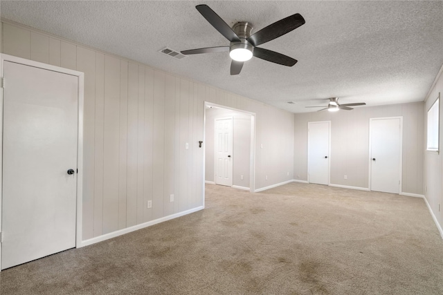 carpeted spare room with ceiling fan and a textured ceiling