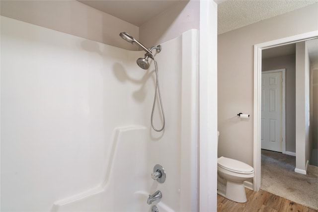 bathroom featuring shower / bathtub combination, toilet, wood-type flooring, and a textured ceiling