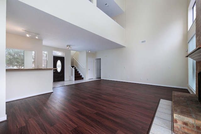 unfurnished living room featuring a fireplace, hardwood / wood-style floors, and a high ceiling