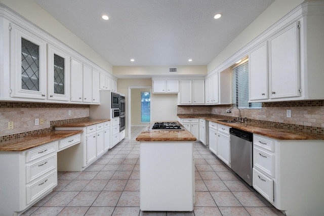 kitchen with stainless steel appliances, sink, light tile patterned floors, white cabinets, and a center island