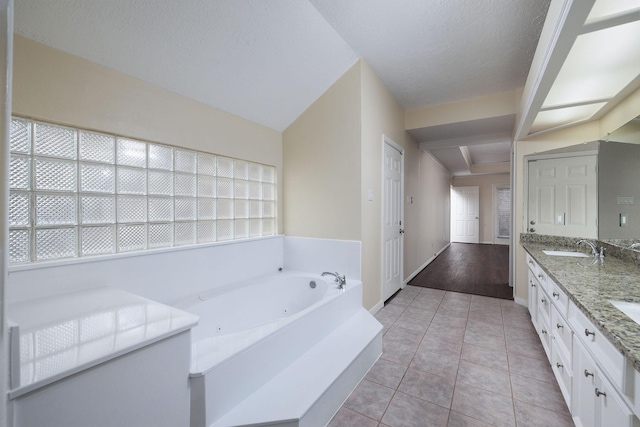 bathroom with a tub to relax in, tile patterned flooring, vanity, and a textured ceiling