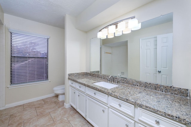 bathroom with tile patterned flooring, a textured ceiling, vanity, and toilet