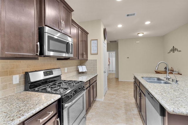 kitchen featuring light stone countertops, appliances with stainless steel finishes, tasteful backsplash, sink, and light tile patterned flooring