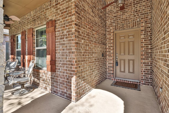 view of exterior entry with ceiling fan and a porch