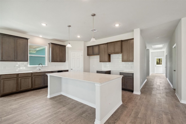 347 Bay Oaks St, La Porte, TX 77571 - kitchen featuring backsplash, a center island, light wood-type flooring, dark brown cabinets, and pendant lighting