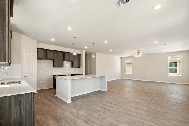 347 Bay Oaks St, La Porte, TX 77571 - kitchen featuring a center island, backsplash, a ceiling fan, dark brown cabinetry, and light wood-style floors