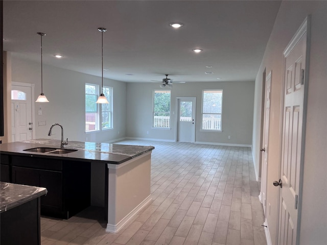 kitchen featuring sink, hanging light fixtures, a kitchen island with sink, ceiling fan, and light hardwood / wood-style floors