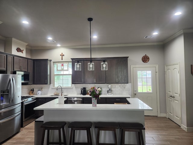 kitchen featuring pendant lighting, a center island, stainless steel appliances, and sink