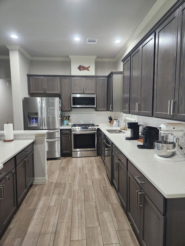 kitchen featuring dark brown cabinets, sink, backsplash, and appliances with stainless steel finishes