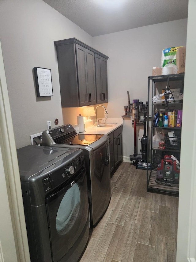 laundry room with hardwood / wood-style flooring, washer and clothes dryer, cabinets, and sink