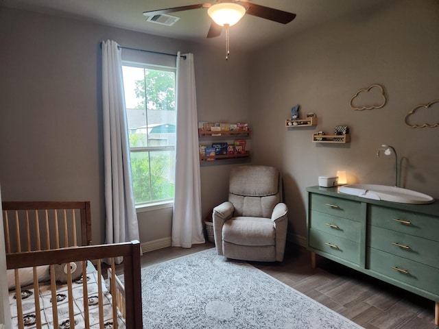 bedroom featuring multiple windows, ceiling fan, light hardwood / wood-style flooring, and a nursery area