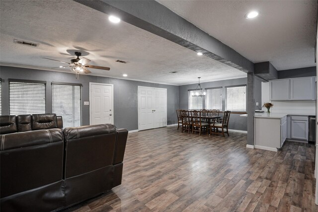 living room featuring ceiling fan with notable chandelier, crown molding, a textured ceiling, and dark wood-type flooring