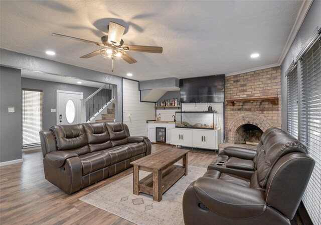 living room with a textured ceiling, a fireplace, wood-type flooring, and crown molding