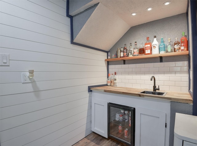 bar with dark hardwood / wood-style flooring, sink, butcher block countertops, wine cooler, and lofted ceiling