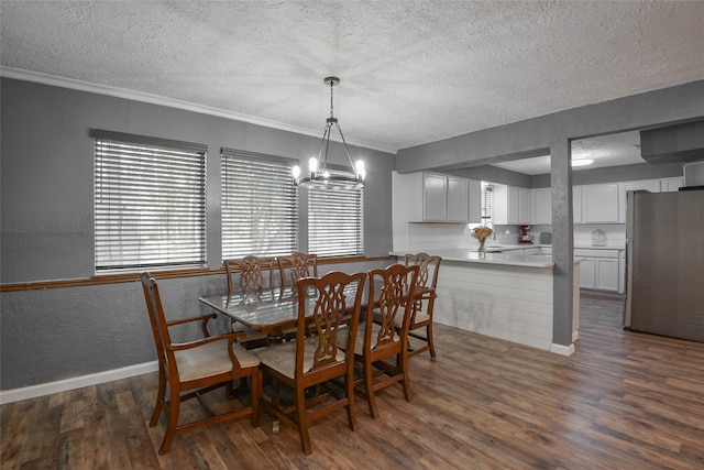 dining area featuring ornamental molding, a textured ceiling, dark wood-type flooring, and a notable chandelier