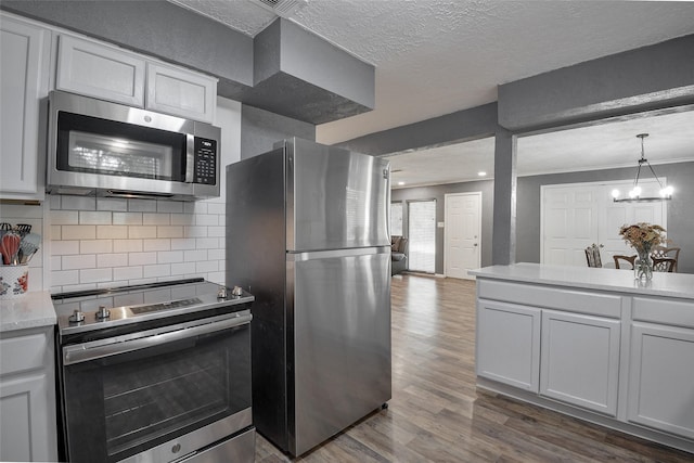 kitchen featuring decorative backsplash, appliances with stainless steel finishes, a textured ceiling, and white cabinets