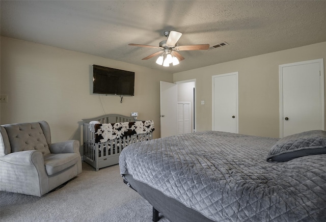 bedroom featuring ceiling fan, light colored carpet, and a textured ceiling