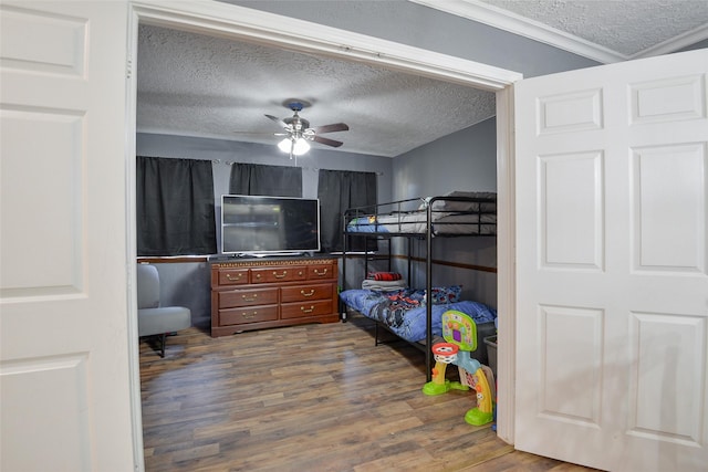 bedroom featuring ceiling fan, crown molding, wood-type flooring, and a textured ceiling