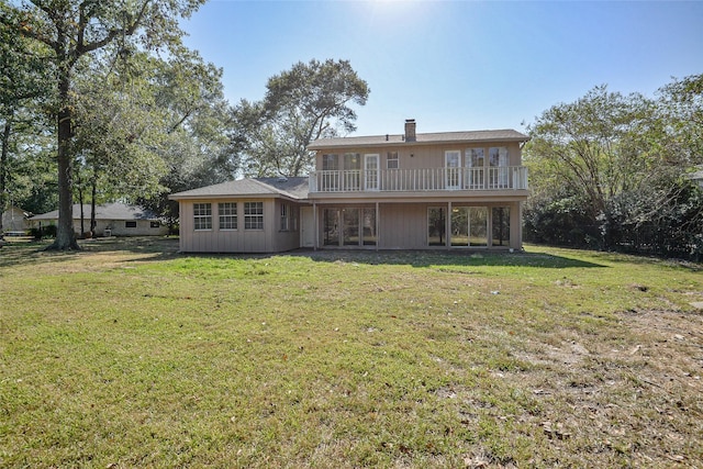 rear view of house featuring a balcony and a yard