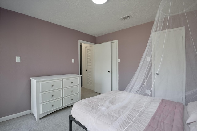 bedroom featuring a textured ceiling and light colored carpet