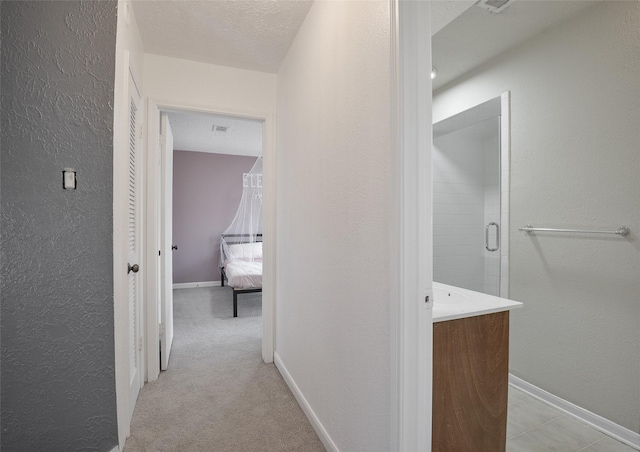 corridor with light colored carpet and a textured ceiling