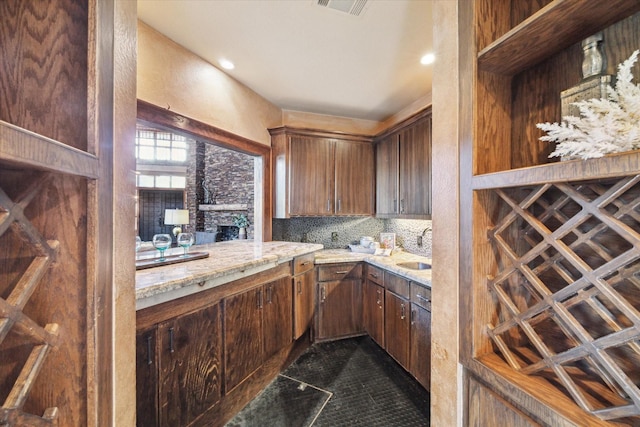 kitchen featuring backsplash, light stone countertops, sink, and dark tile patterned flooring