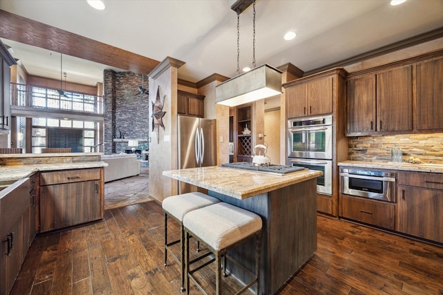 kitchen with pendant lighting, a breakfast bar, a center island, dark hardwood / wood-style floors, and appliances with stainless steel finishes