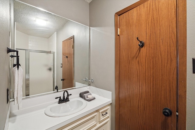 bathroom featuring vanity, a shower with shower door, and a textured ceiling