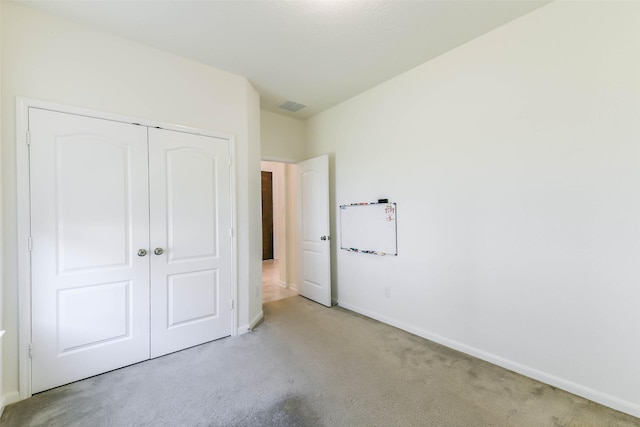 unfurnished bedroom with a closet and light colored carpet