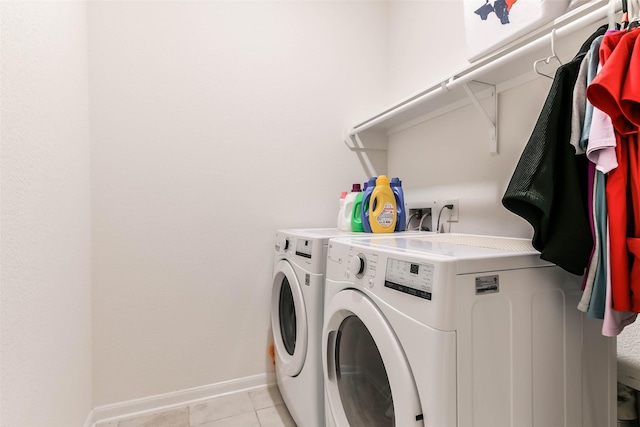 laundry area with washing machine and clothes dryer and light tile patterned floors