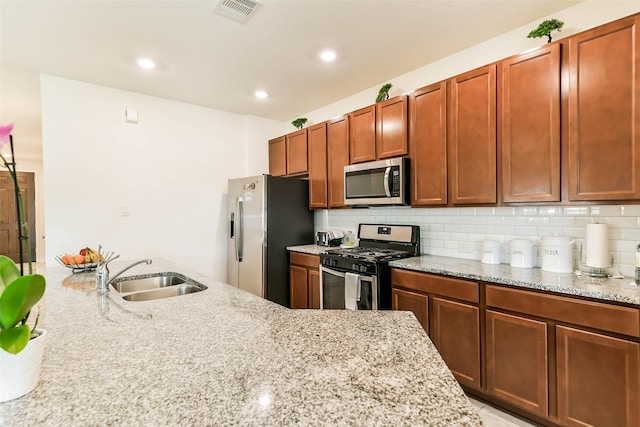 kitchen with tasteful backsplash, light stone counters, sink, and stainless steel appliances