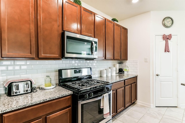 kitchen with light tile patterned floors, backsplash, stainless steel appliances, and light stone counters