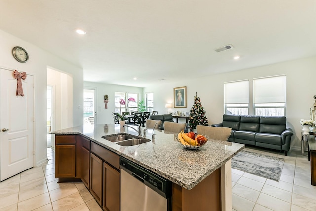 kitchen featuring sink, light stone counters, stainless steel dishwasher, a center island with sink, and light tile patterned floors