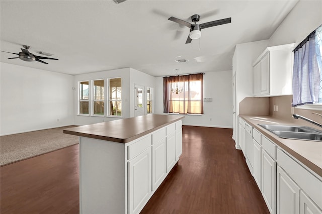 kitchen with a kitchen island, sink, dark hardwood / wood-style floors, white cabinetry, and hanging light fixtures