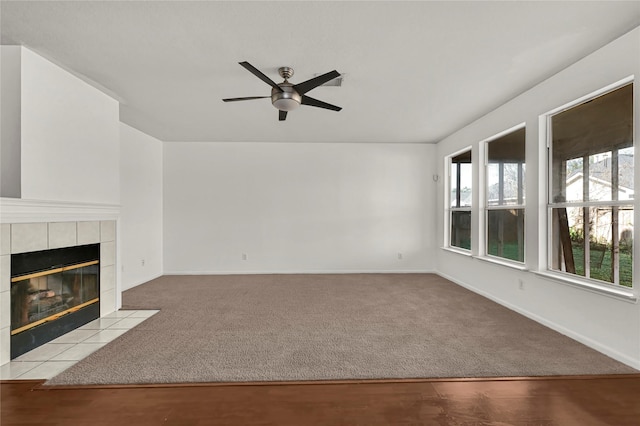 unfurnished living room with ceiling fan, a fireplace, and light carpet