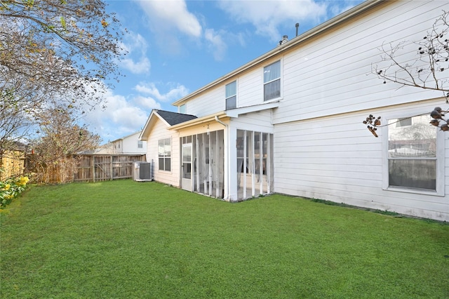 back of property featuring a lawn, a sunroom, and central air condition unit