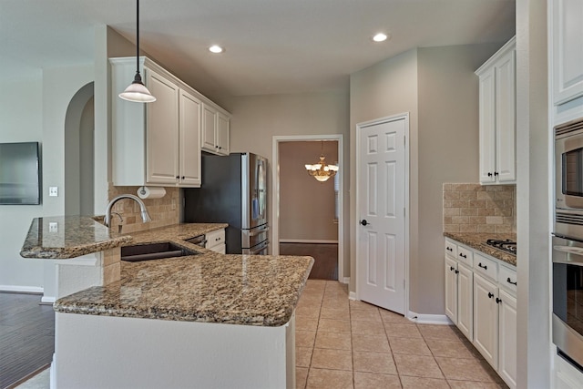 kitchen with kitchen peninsula, white cabinetry, hanging light fixtures, and sink