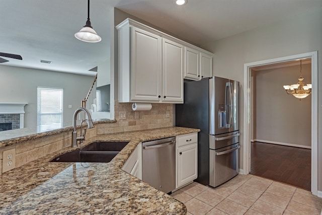 kitchen with decorative backsplash, appliances with stainless steel finishes, sink, light tile patterned floors, and white cabinets